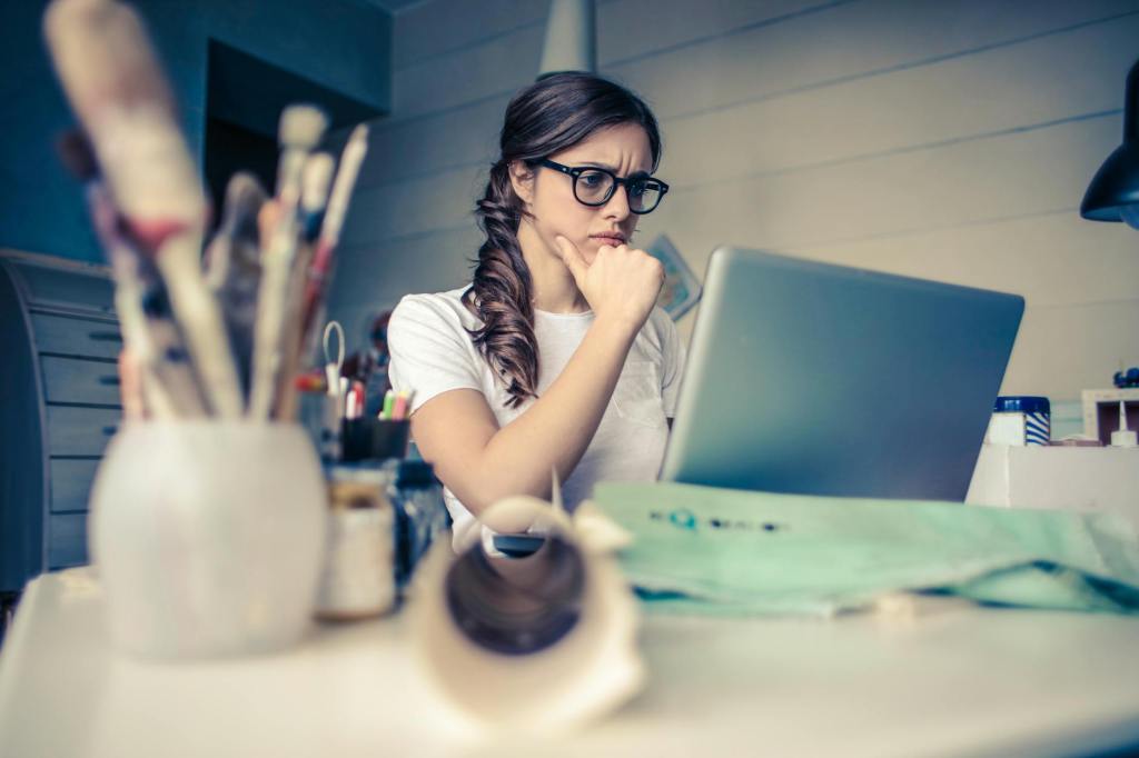 A woman in glasses looking at a lap top screen